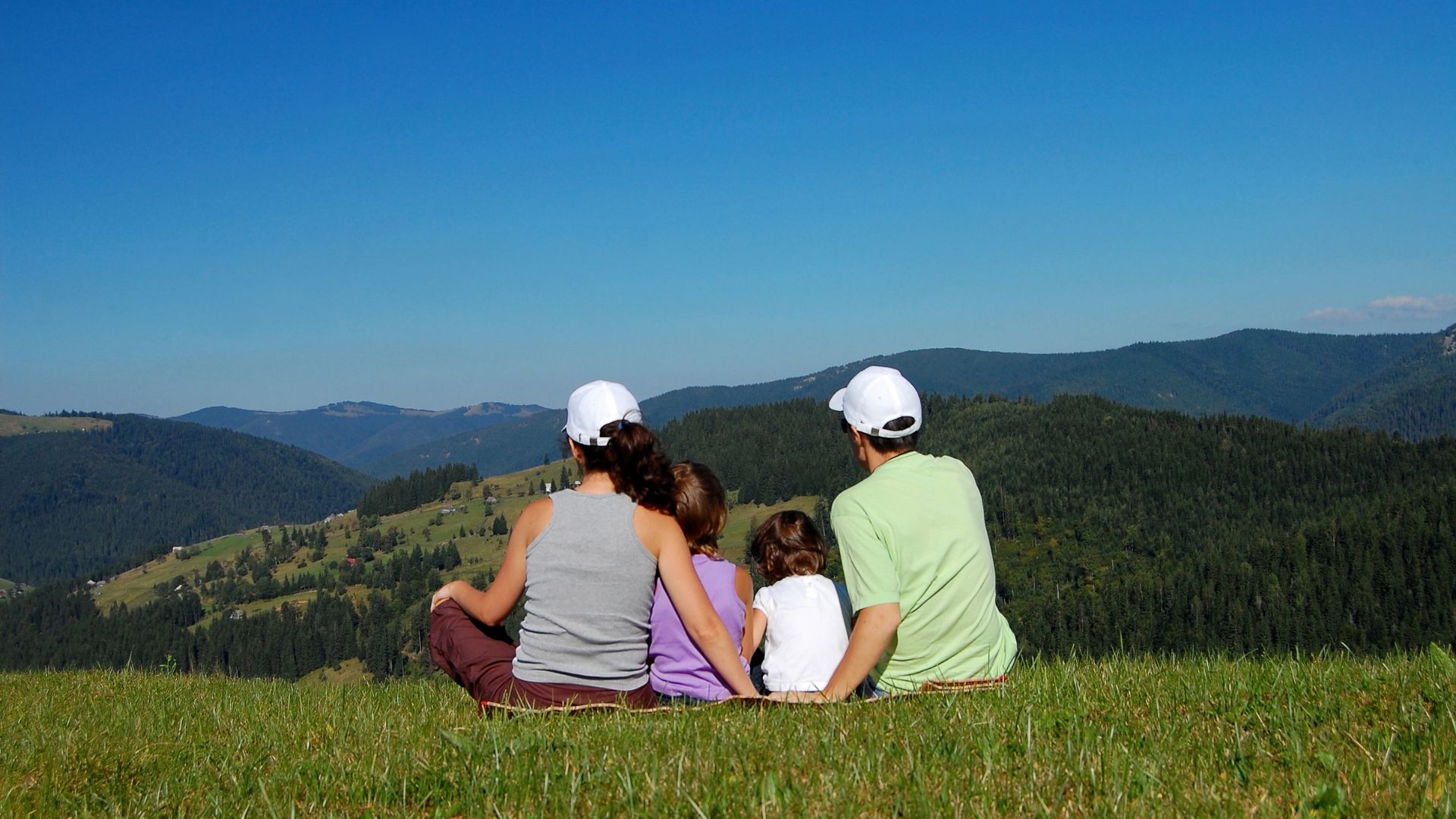 A Group Of People Sitting On A Hill Overlooking A Valley