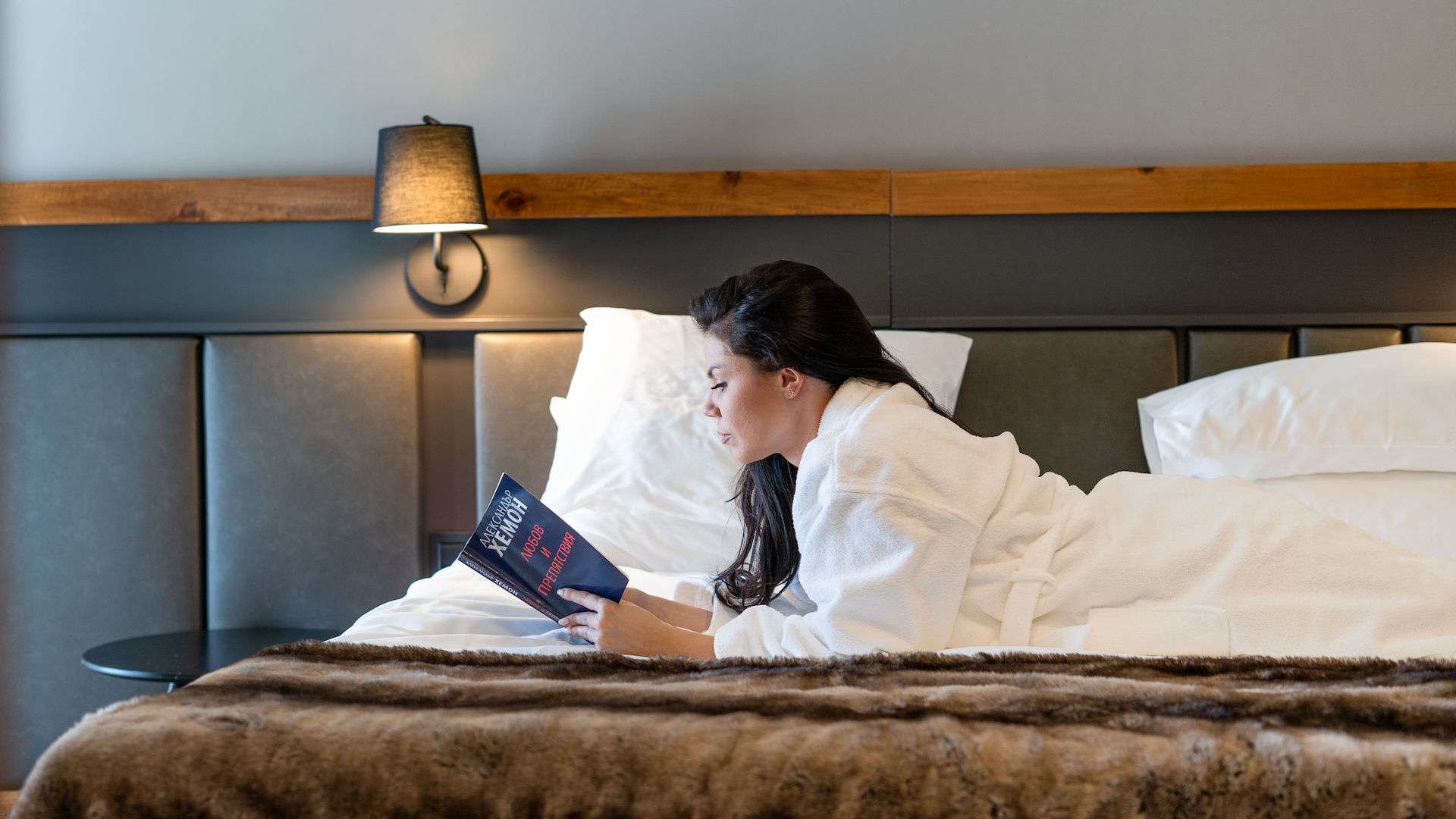 A Person Reading A Book On A Bed