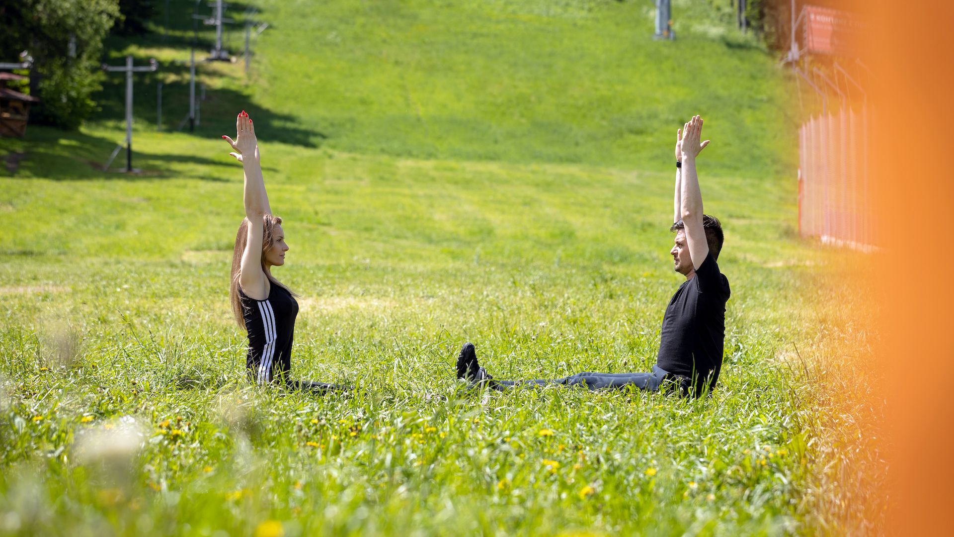 A Man And Woman Doing Yoga In A Grassy Field