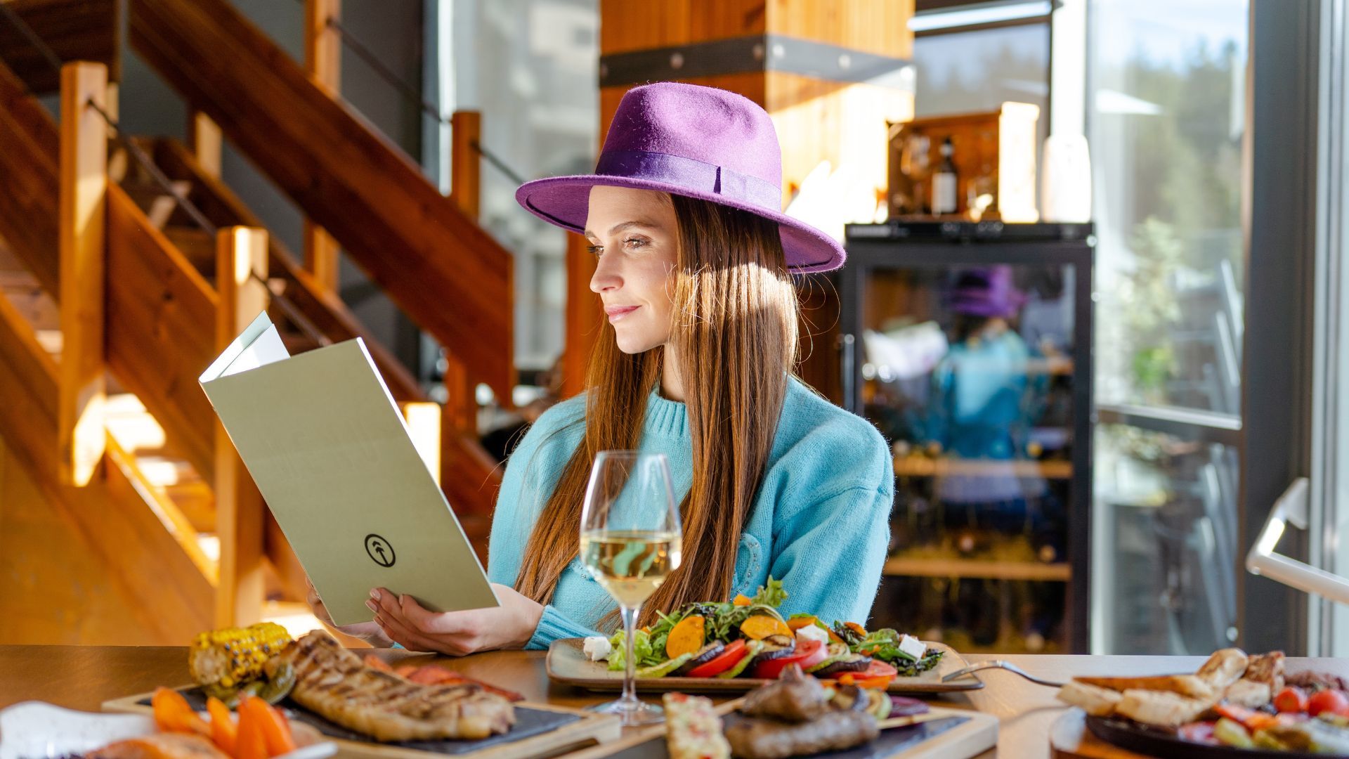 A Woman In A Purple Hat Holding A Laptop And A Glass Of Wine